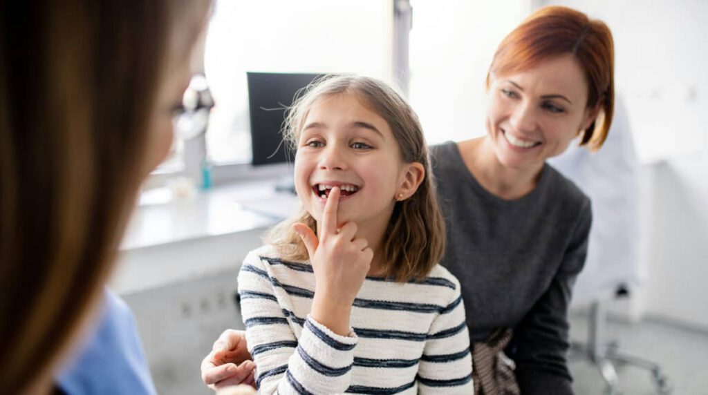 a little girl sitting in a paediatric dentist’s chair