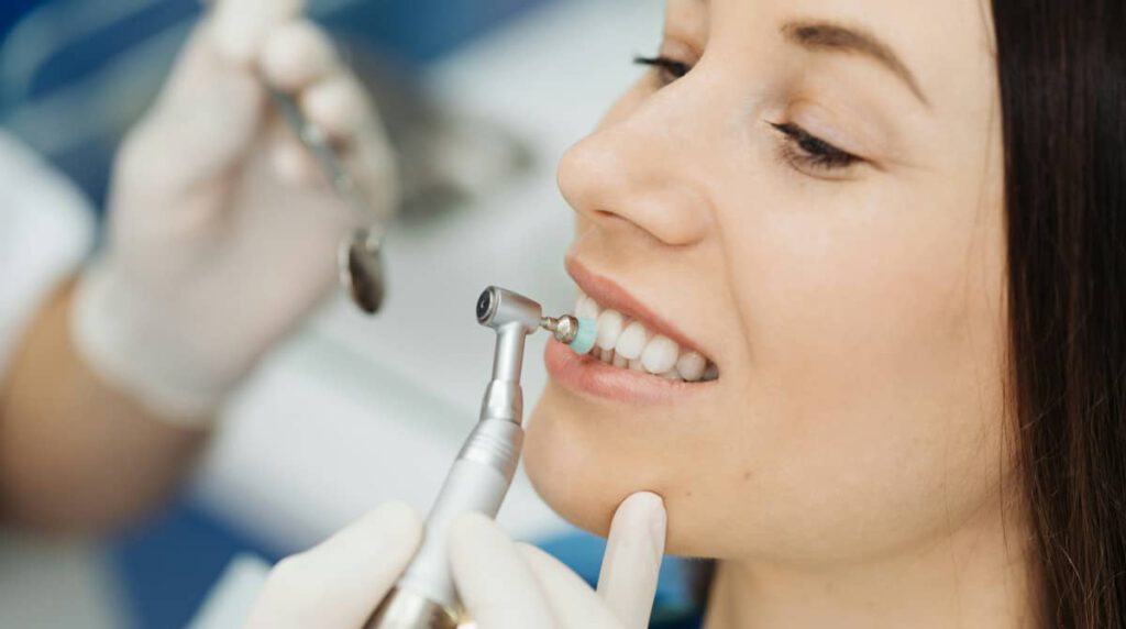 Una persona sonríe mostrando dientes blancos y sanos mientras está en una consulta dental. Su sonrisa refleja la importancia del cuidado de las carillas dentales y la higiene bucal adecuada.